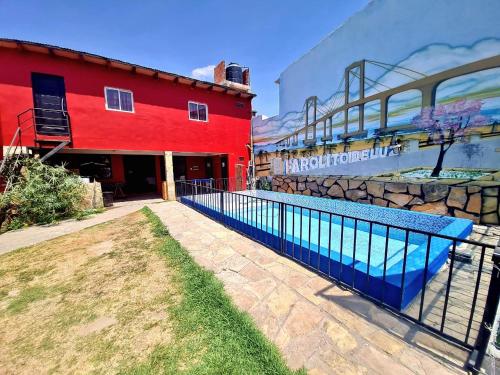 a red building with a blue fence in front of it at Farolito de Luz Apart in Salta