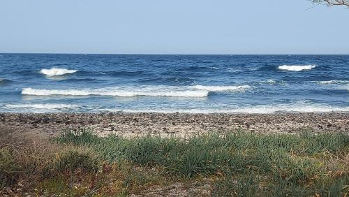 a beach with some waves in the ocean at Sea breeze houses in Monolithos