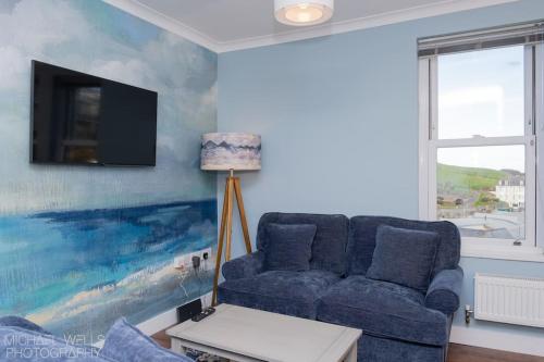 a living room with a blue couch and a painting at Capstone's Lookout near tunnels beach in Ilfracombe