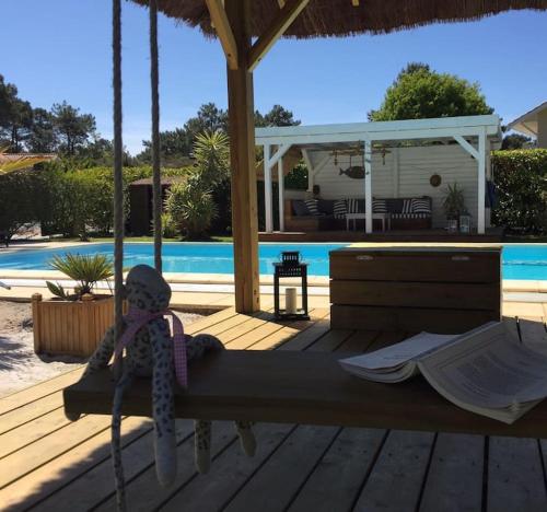 un squelette de jouet assis sur un hamac sur une terrasse à côté d'une piscine dans l'établissement VILLA PROCHE MER/PISCINE CHAUFFEE ET SECURISEE/CLIMATISATION, à Lacanau-Océan