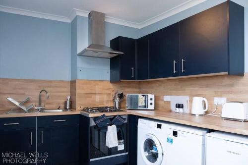 a kitchen with black cabinets and a washer and dryer at Capstone's Lookout near tunnels beach in Ilfracombe