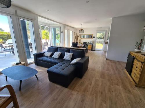 un salon avec un canapé noir et une table dans l'établissement VILLA PROCHE MER/PISCINE CHAUFFEE ET SECURISEE/CLIMATISATION, à Lacanau-Océan