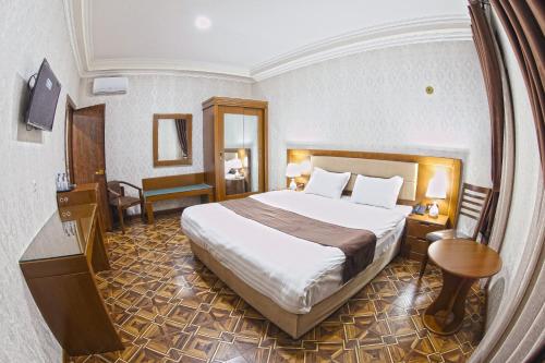 ブハラにあるCARAVAN PLAZA BOUTIQUEの大きなベッドとテーブルが備わるホテルルームです。