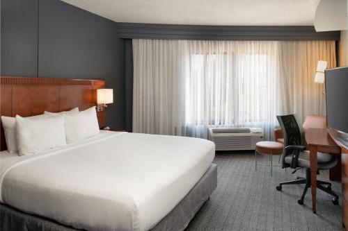 a hotel room with a large bed and a desk at Courtyard Memphis Collierville in Collierville