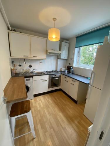 een keuken met witte kasten en een houten vloer bij Richmond studio flats in Kew Gardens