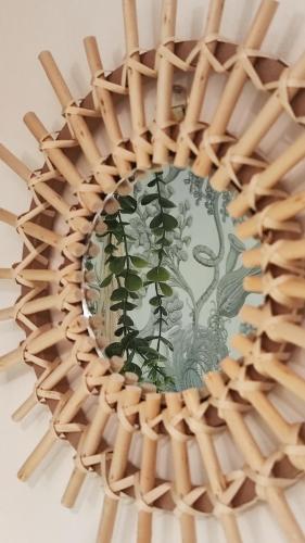 un miroir rond en rotin avec une peinture de plantes dans l'établissement Le Petit Catalan, à Marseille