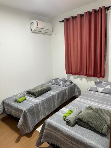 two beds in a room with a red curtain at APTO COMPLETO - MORADA DO OURO in Cuiabá