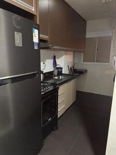 a kitchen with a black refrigerator and a stove at APTO COMPLETO - MORADA DO OURO in Cuiabá