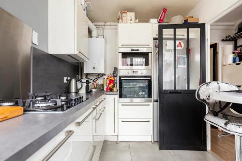 a kitchen with white cabinets and a black refrigerator at Stud SDB perso et taxi CDG extra in Aulnay-sous-Bois