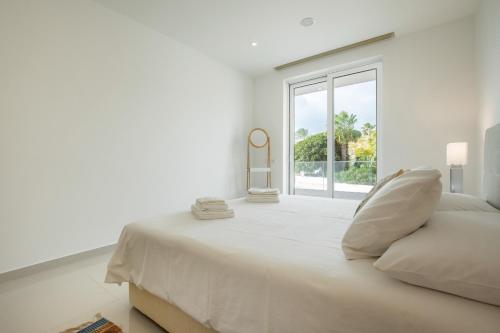 a white bedroom with a large bed and a window at Casa Lilou - Luxury Oceanview Penthouse in Lagos