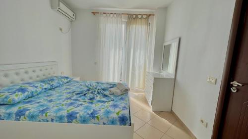 a bedroom with a bed with a blue comforter at Queen Residence in Shëngjin