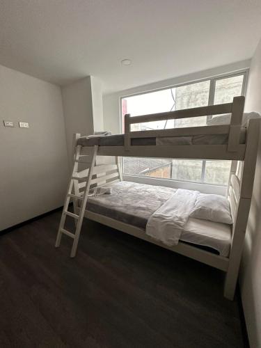 a bunk bed with a ladder in a room with a window at Hermoso apartamento, capacidad 8 personas in Pasto