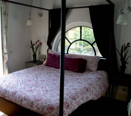 1 dormitorio con cama con dosel y ventana en Villa Giotto, en Fortunago