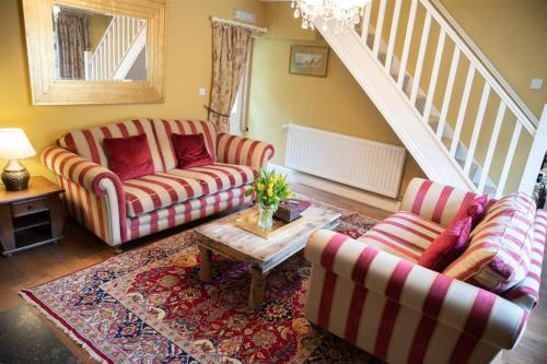 a living room with two couches and a table at Gardeners Cottage in Longwitton