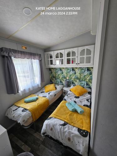 two beds in a room with yellow and blue sheets at Kates Home Lagganhouse Woodland Way 19 in Ballantrae
