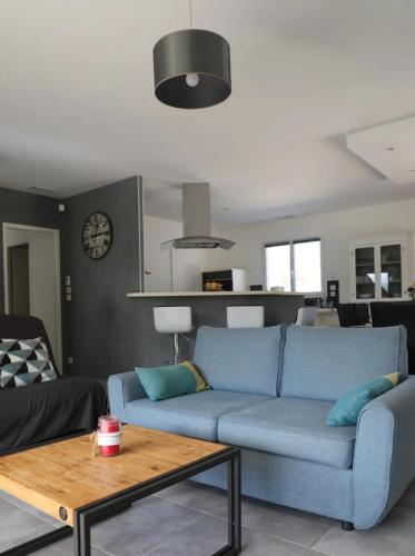 un salon avec un canapé bleu et une table dans l'établissement L'Olivier, à Montoison
