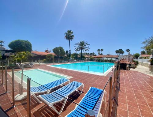 a swimming pool with lounge chairs in front of a resort at Bungalow con jardín privado junto al Yumbo in Playa del Ingles