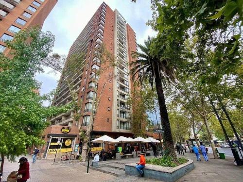 a tall building with people sitting in front of it at Apartmento en providencia in Santiago