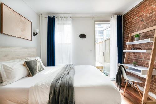ein Schlafzimmer mit einem weißen Bett und einer Ziegelwand in der Unterkunft 24-4 New Private Terrace W D Apt Prime Gramercy in New York