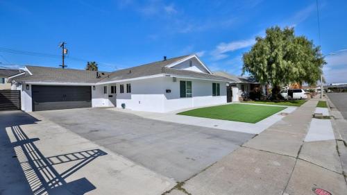 a large white house with a driveway at H&H Modern Lux 4BD 1 King Suite 3 Queen SoCal Disney in Westminster