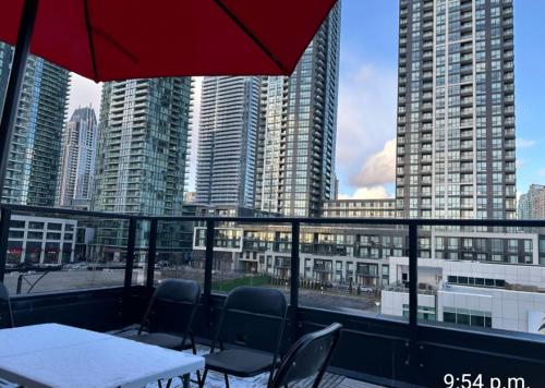 a table and chairs on a balcony with tall buildings at Modern Luxury 3 bed rooms House in Toronto Mississauga in Mississauga