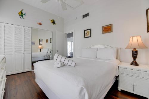 a white bedroom with two beds and a lamp at Villa Coastal by Brightwild-Pool & Free Parking in Key West