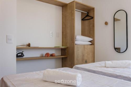 2 camas en una habitación con espejo y estanterías en TMH - Condomínio Essence em Porto de Pedras/AL, en Porto de Pedras