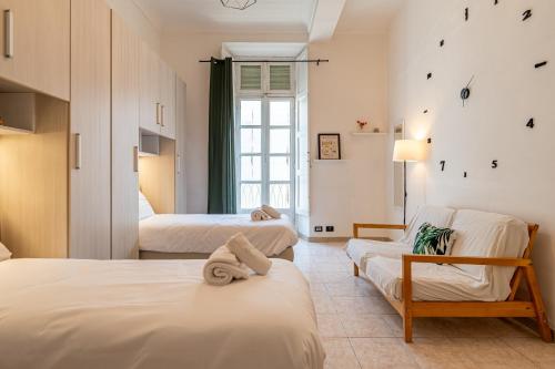 a bedroom with two beds and a chair and a window at La casa di Levi, in centro a Torino in Turin