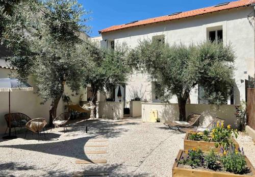 une cour avec des arbres et des chaises ainsi qu'un bâtiment dans l'établissement Villas Maya 1 -  Salonenque - AVIGNON - Terrasse -, à Avignon