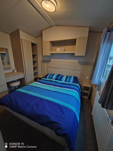 a bedroom with a large bed with blue sheets at Ocean Edge Holiday Park in Heysham