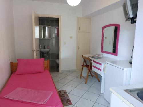 a small room with a pink bed and a kitchen at Ανεξάρτητο studio κοντά στο κέντρο της Πάτρας. in Patra