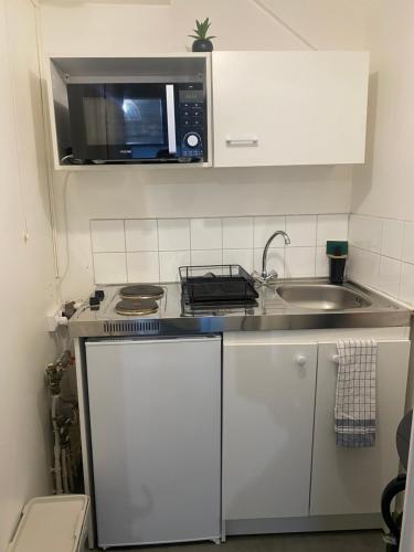 a small kitchen with a microwave and a sink at Chambre privée Sdb kitchenette proche de Paris in Saint-Ouen