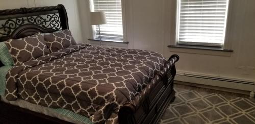 a bedroom with a bed with a brown comforter and two windows at A cozy quiet place to be at peace in Wakefield