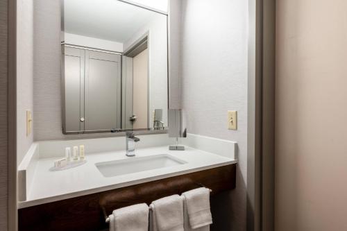 a bathroom with a sink with a mirror and towels at Courtyard Columbus Airport in Columbus