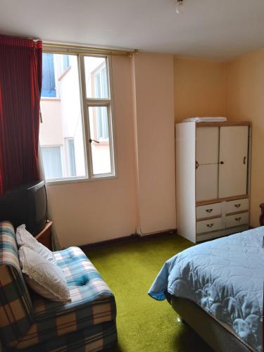 a bedroom with a bed and a window and a couch at Alojate y Descansa in Bogotá