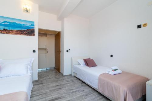 two beds in a room with white walls and wooden floors at Aldino Rooms in Trogir