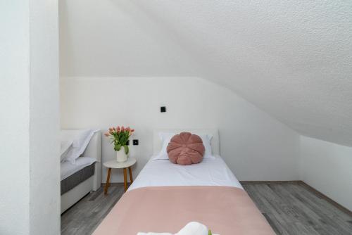 a white room with a bed with two pillows on it at Aldino Rooms in Trogir