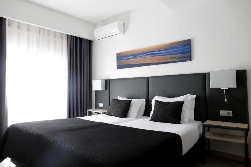 um quarto com uma cama em preto e branco e uma janela em Hotel M em Espinho