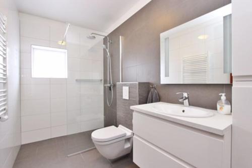 La salle de bains blanche est pourvue de toilettes et d'un lavabo. dans l'établissement Asa´s comfortable, cozy nest in the north., à Akureyri