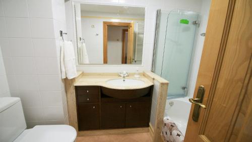 La salle de bains est pourvue d'un lavabo, d'un miroir et de toilettes. dans l'établissement Apartamento de Castro 2º IZ, à Ponteceso