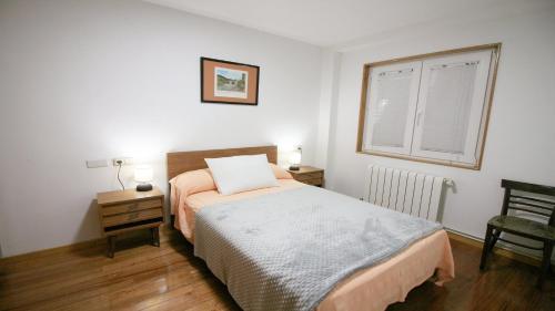 1 dormitorio con cama, ventana y silla en Apartamento de Castro 2º IZ, en Ponteceso