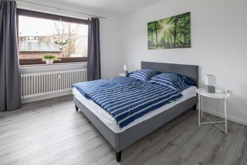 Un dormitorio con una cama con sábanas azules y blancas y una ventana en Biebrach's Ferienwohnungen, en Wilhelmshaven