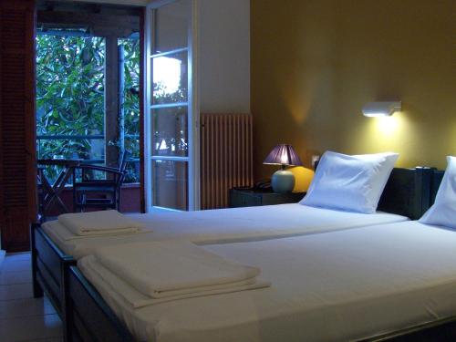 a bedroom with two beds and a door to a balcony at Anesis Hotel in Agios Ioannis Pelio