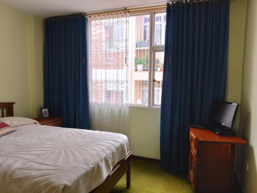 a bedroom with a bed and a window with blue curtains at Alojate y Descansa in Bogotá
