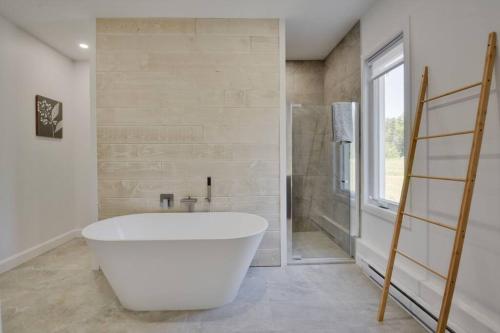 een badkamer met een groot wit bad en een douche bij Cottage Quebec - La Zeolite in Petite-Rivière-Saint-François