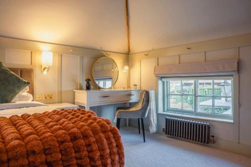 a bedroom with a bed and a desk and a window at Chris Wheeler at The Crown Inn in Buckinghamshire