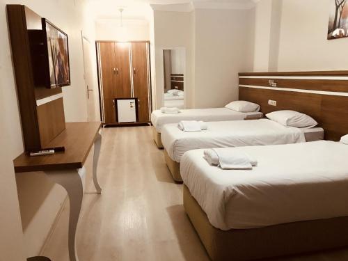 a hotel room with four beds and a television at Larok Hotel in Akcaabat