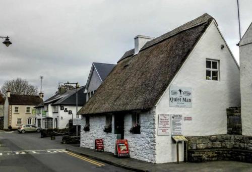 an old white building with a roof on a street at Carraig Ban in Cong