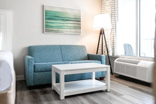 a living room with a blue chair and a table at Perry's Ocean-Edge Resort in Daytona Beach