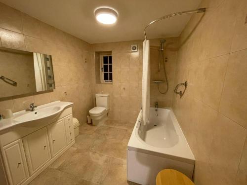 a bathroom with a tub and a toilet and a sink at The Barn at Rigg End in Rosedale Abbey
